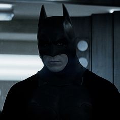 the dark knight is standing in an empty room with his head turned to look like he's wearing a batman mask