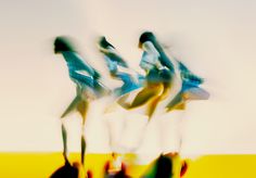 blurry photograph of three people jumping in the air with their legs spread out and arms extended