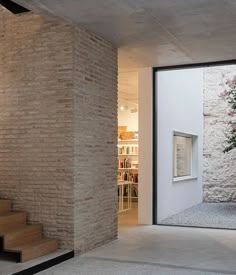 an open door leading to a room with stone walls and stairs, in front of a brick wall