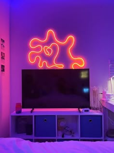 a television sitting on top of a tv stand in a room with neon lights above it