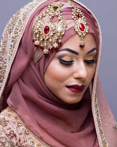 a woman wearing a hijab with red jewels on her head and makeup is looking at the camera