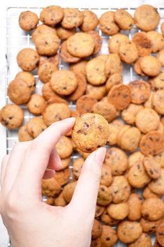 a person holding a cookie in front of a bunch of cookies