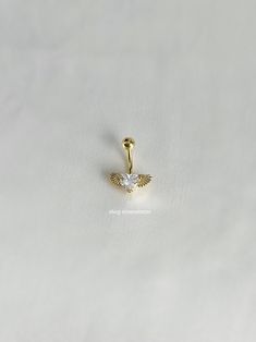 a gold nose ring with an angel wing on it's side, sitting on a white surface