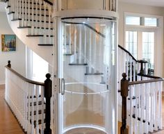 a spiral stair case in the middle of a room with wooden floors and white railings