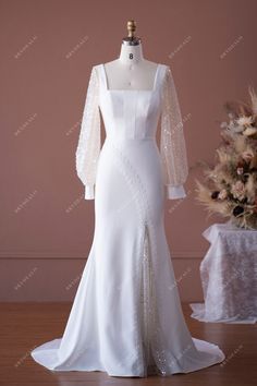 a white wedding dress with long sleeves and beadings on the bouncy