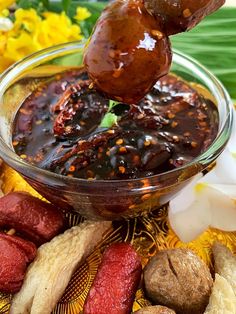 a person dipping some kind of food into a glass bowl with other foods around it