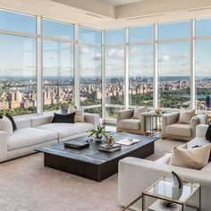 a living room filled with lots of furniture and large windows overlooking the cityscape