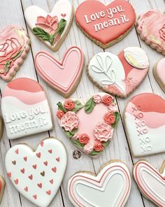 heart shaped cookies are arranged on a white table with pink roses and hearts in the middle