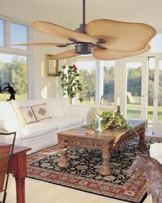 a living room filled with furniture and a ceiling fan in the middle of an open floor plan