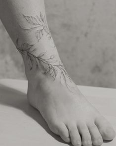 a black and white photo of a person's foot with a flower tattoo on it