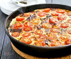 an omelet with tomatoes in a pan on a wooden table