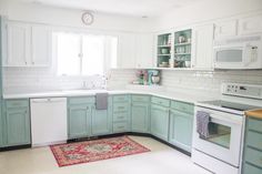 a kitchen with blue cabinets and white appliances, rug on the floor in front of the sink