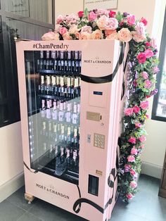 a pink champagne vending machine with roses around it