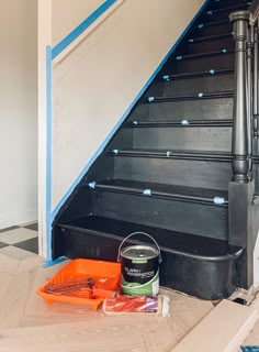 a can of paint sitting on the ground next to some stairs with blue tape around it