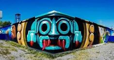 a colorful face painted on the side of a building in front of a blue sky