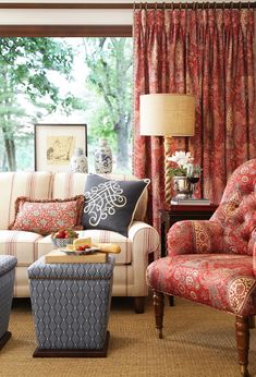 a living room filled with furniture next to a window covered in red and blue curtains