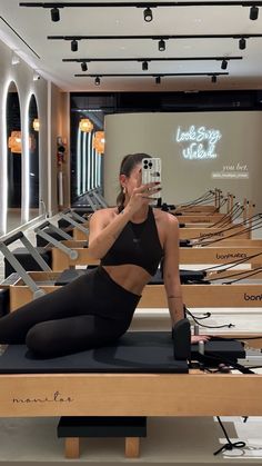 a woman is taking a selfie while sitting on a pilatesr in the gym