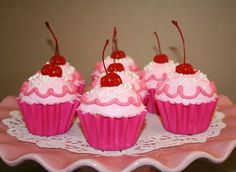 pink cupcakes with cherries and white frosting on a pink plate, ready to be eaten