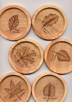 four wooden plates with engraved leaves on them