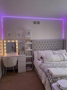 a white bed sitting next to a desk with a laptop on top of it in a bedroom