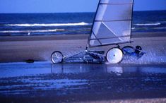 a small sailboat on the beach with it's front wheel in the water