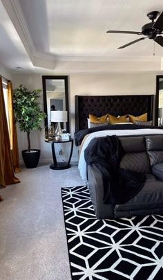 a black and white bedroom with a bed, couch, lamps and mirror on the wall