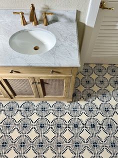 a white sink sitting next to a wooden cabinet under a bathroom mirror on top of a tiled floor