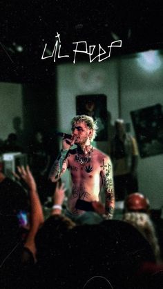 a man with tattoos on his chest holding a microphone in front of a group of people