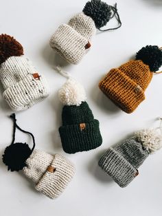 knitted hats and mittens laid out on a white surface, with one hat hanging from the top