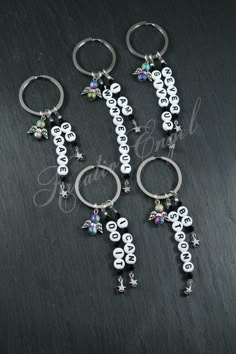 four different key chains with charms attached to them on top of a black surface,