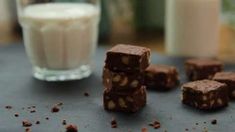 several pieces of chocolate sitting on top of a table next to a glass of milk