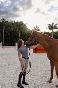 a woman standing next to a brown horse