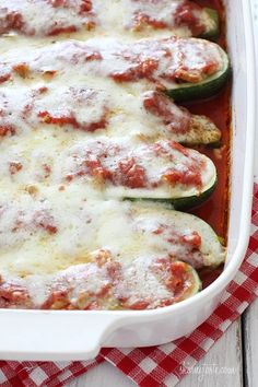 stuffed zucchini boats with sauce and cheese in a white casserole dish