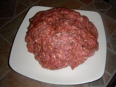 a white plate topped with meatballs on top of a tiled counter next to a knife