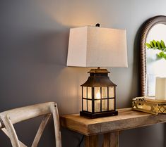 a wooden table with a lamp on it next to a mirror