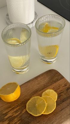 two lemons on a cutting board next to some glasses