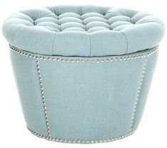 a small blue ottoman with studded trimmings on the top and bottom, in front of a white background