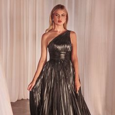 a woman standing in front of a curtain wearing a black and silver dress with one shoulder