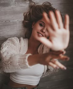 a woman in white shirt laying on wooden floor with her hands out to the side