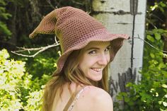 a woman wearing a crocheted hat in the woods