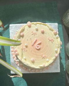 a cake with pink icing and flowers on it sitting on a green tablecloth