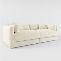 a white couch sitting on top of a floor next to a gray wall in front of it