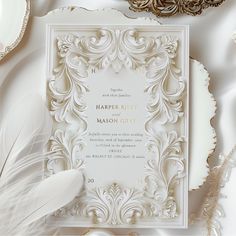 a white wedding card with a feather on it