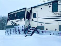 an rv is parked in the snow with its ladder up to it's roof