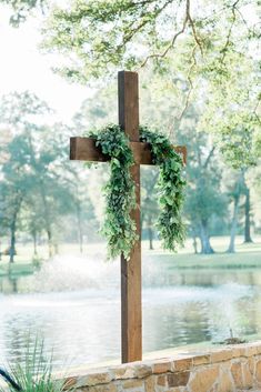 a cross with greenery on it sitting in front of a lake