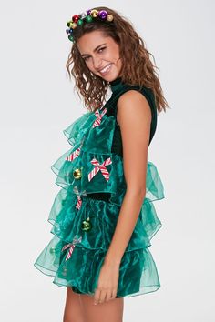 a woman wearing a green dress with christmas decorations on it