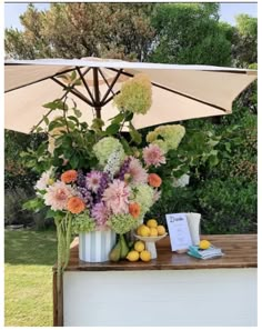 a table with flowers and fruit under an umbrella