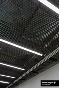 the ceiling in an office building is covered with metal mesh and has three lights on each side