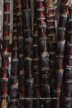 several bundles of red bamboo sticks are stacked up in a row and ready to be sold