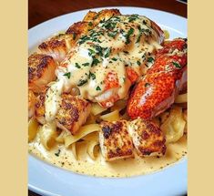 lobster and pasta on a white plate with parsley sprinkled in butter sauce